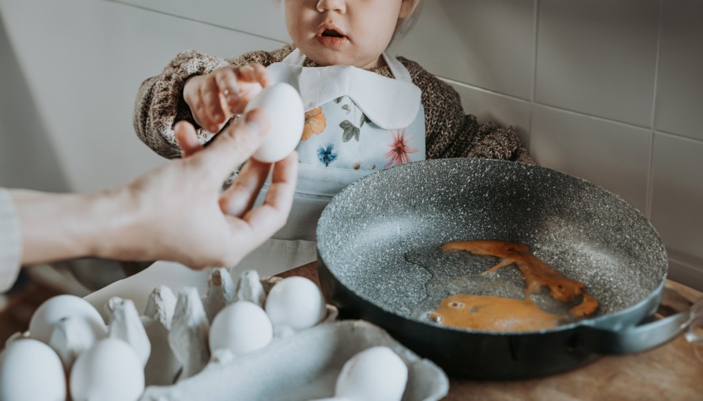 Zoja w kuchni, która z pomocą taty przygotowuje śniadanie. Wojtek podaje jej jajka, które Zoja umiejętnie wbija na patelnię. To nie tylko nauka samodzielności dla niej, ale też chwila, w której cała rodzina może cieszyć się wspólnym czasem podczas codziennych obowiązków