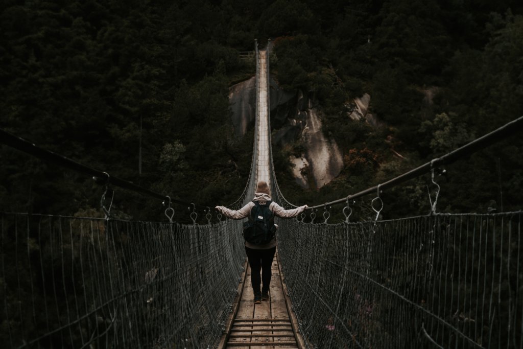 Angelika przemierzająca most Handeckfallbrücke, otoczona przez bujny las szwajcarski, z rwącą rzeką płynącą 70 metrów poniżej.